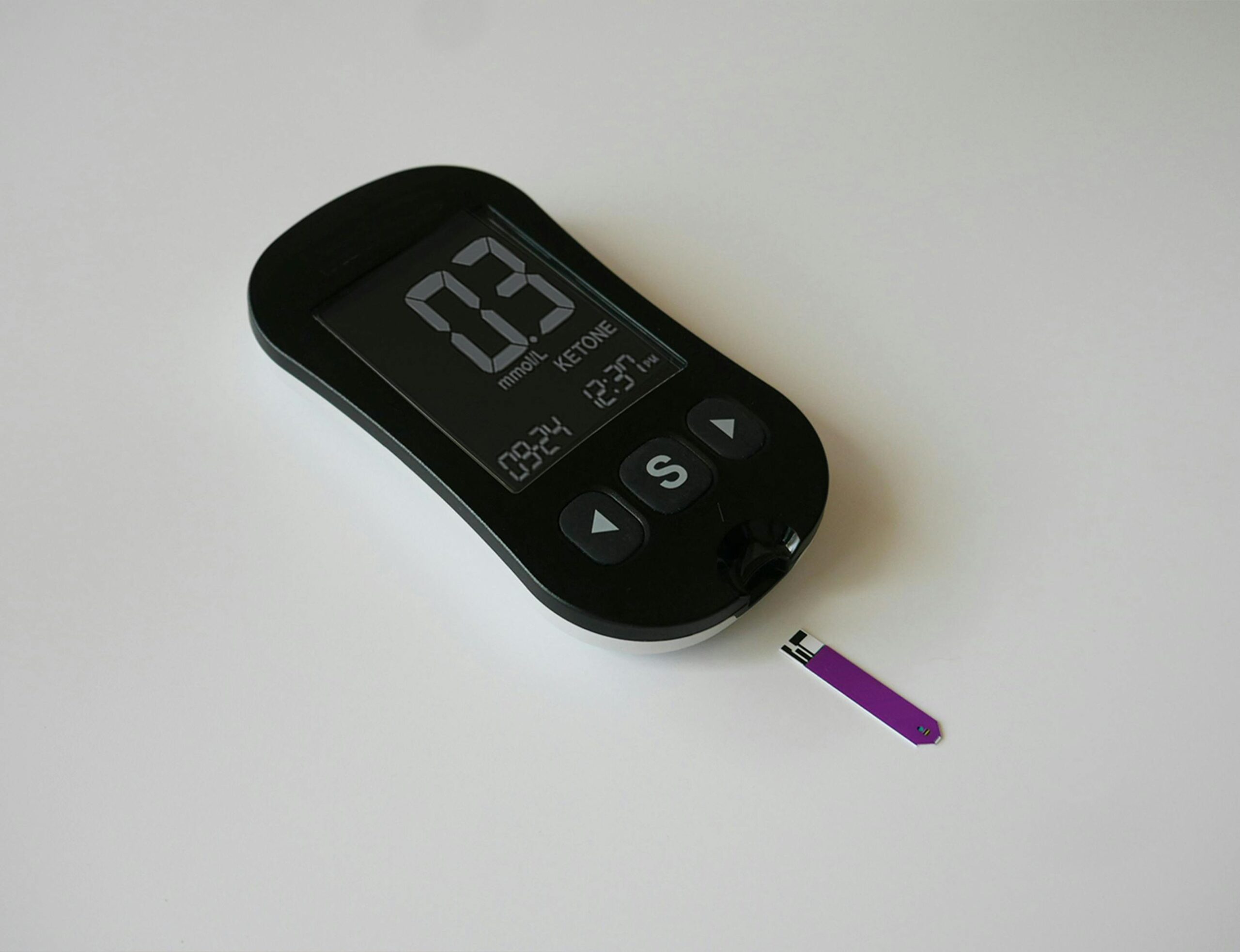 A close-up of a digital ketone meter on a plain surface, ideal for health tracking imagery.